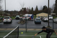 Myles Baida plays pickleball after emergency responders put a homeless person in an ambulance on Saturday, March 23, 2024, in Grants Pass, Ore. Relatives had called police and requested a welfare check. (AP Photo/Jenny Kane)