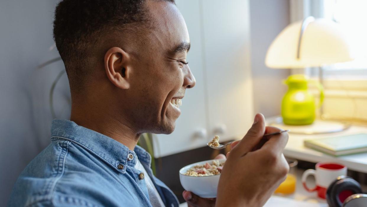 young african american man eating healthy snack at home