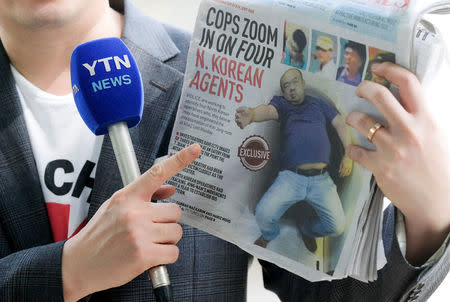 A reporter holds up a local newspaper during his report in front of the morgue at Kuala Lumpur General Hospital where Kim Jong Nam's body is held for autopsy in Malaysia February 18, 2017. REUTERS/Athit Perawongmetha