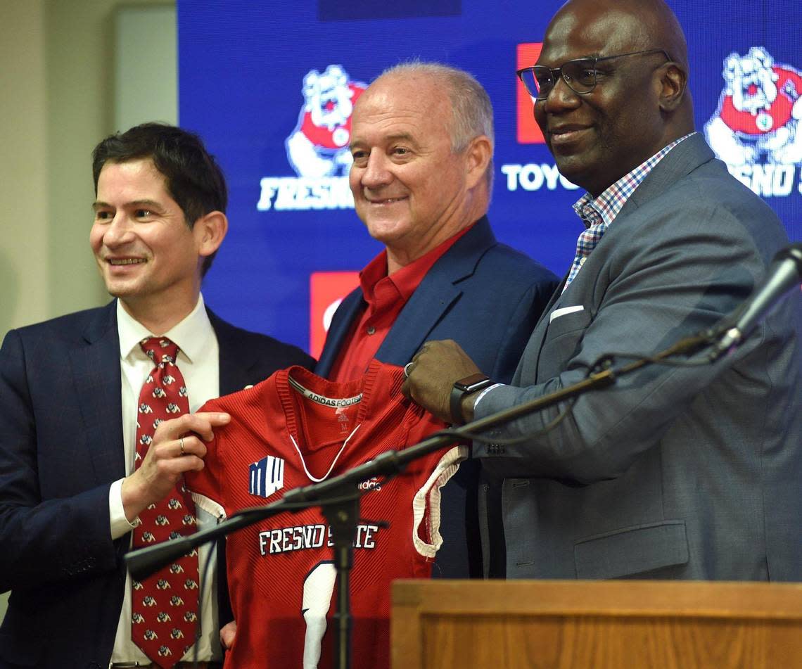 Fresno State’s Jeff Tedford, flanked by university President Saúl Jiménez-Sandoval, left, and athletics director Terry Tumey, hold up a jersey after a December 2021 news conference reintroducing Tedford as football coach.