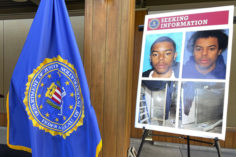 An FBI flag and a seeking information posterboard are set up next to a podium ahead of a press conference at the FBI field office in Portland, Ore., on Wednesday, Aug. 2, 2023. The posterboard displays photos of Negasi Zuberi, an Oregon man facing a federal charge of interstate kidnapping, and photos of the makeshift cinderblock cell in the basement of his home in Klamath Falls, Oregon, where he allegedly held a woman that he is accused of kidnapping from Seattle. (AP Photo/Claire Rush)