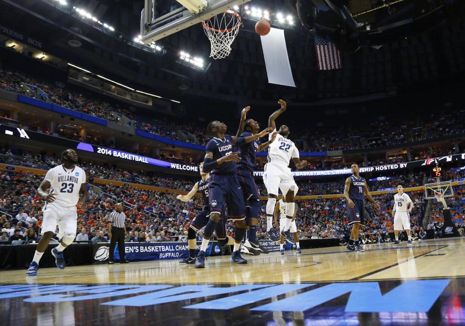 Villanova's JayVaughn Pinkston (22) shoots over Connecticut's DeAndre Daniels and Amida Brimah (35) during the first half of a third-round game in the NCAA men's college basketball tournament in Buffalo, N.Y., Saturday, March 22, 2014. (AP Photo/Bill Wippert)