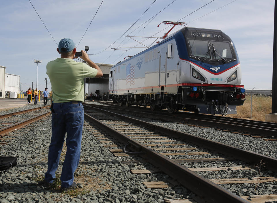 In this photo taken Saturday, May 11, 2013, Dave Ward, vice president of Locomotives for the Siemens Rail Systems, takes a picture of one of the new Amtrak Cities Sprinter Locomotive built by Siemens in Sacramento, Calif. The new electric locomotive, one of three of 70 to be built, will run on the Northeast intercity rail lines and replace Amtrak locomotives that have been in service for 20 to 30 years.(AP Photo/Rich Pedroncelli)