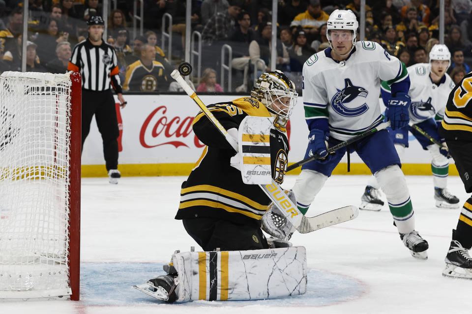 Boston Bruins goaltender Linus Ullmark, front left, makes a save off his shoulder as Vancouver Canucks' Brock Boeser looks for a rebound during the third period of an NHL hockey game Sunday, Nov. 13, 2022, in Boston. (AP Photo/Winslow Townson)