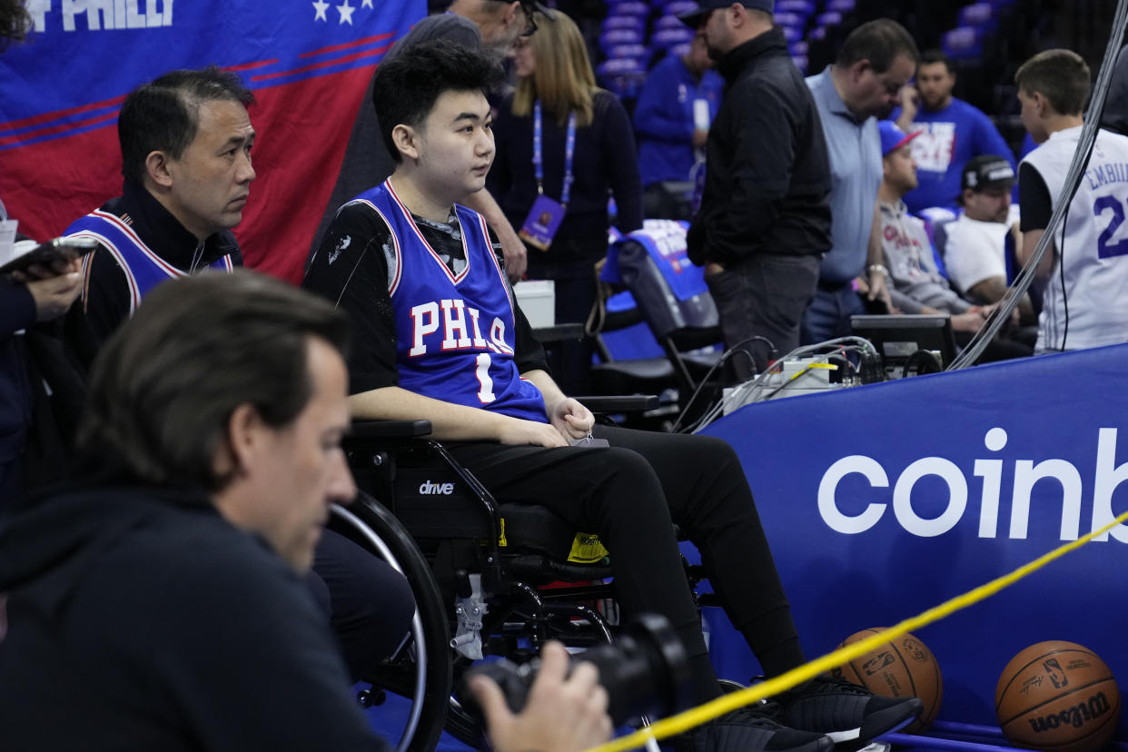 John Hao, second from left, watches warm ups ahead of Game 4 in an NBA basketball Eastern Conference semifinals playoff series between the Philadelphia 76ers and the Boston Celtics, Sunday, May 7, 2023, in Philadelphia. 76ers' James Harden invited Hao, a student severely wounded in a Feb. 13 mass shooting at Michigan State University, to view the game. (AP Photo/Matt Slocum)