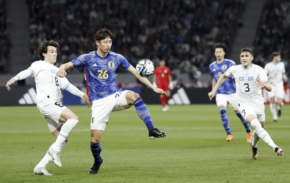 Uruguay's Facundo Pellistri, left, and Japan's Hiroki Ito battle for the ball in the first half of their friendly soccer match at the National Stadium in Tokyo, Friday, March 24, 2023. (Kyodo News via AP)