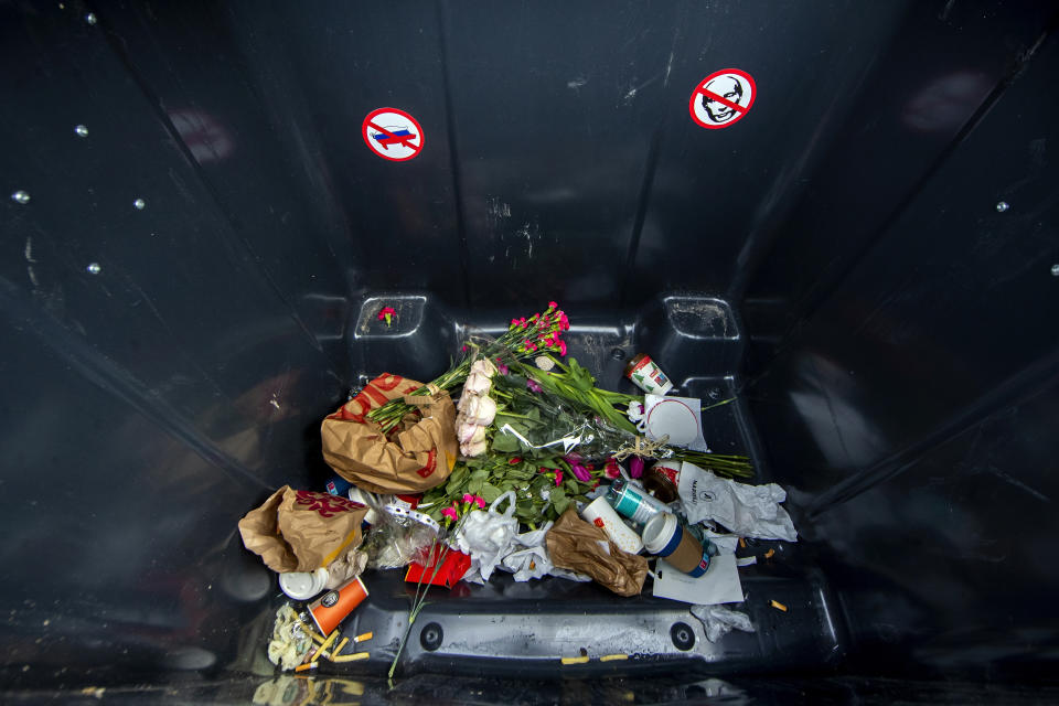 Flowers are seen amongst other garbage inside a garbage container which displayed a sign with writing reading "For carnations, candles and Soviet nostalgia", after flowers were laid by ethnic Russians on a destroyed Russian tank T-72B installed as a symbol of war marking the first anniversary of Russia's full-scale invasion of Ukraine, at Cathedral Square in Vilnius, Lithuania, Wednesday, March 1, 2023. Some ethnic Russians in the Baltic states have placed flowers at displays of burnt-out Russian tanks seized by Ukrainians, making a gesture of homage and support for Russia's war against Ukraine. (AP Photo/Mindaugas Kulbis)