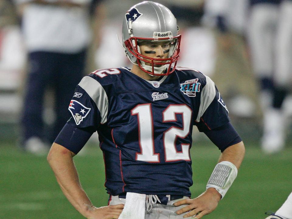 Tom Brady kneels on the field with his hands on his hips during a game in 2008.
