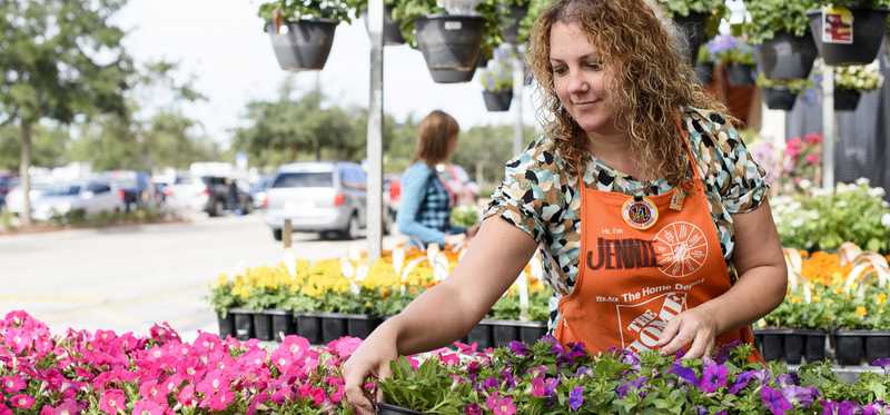 Female Home Depot employee arranges flowers.