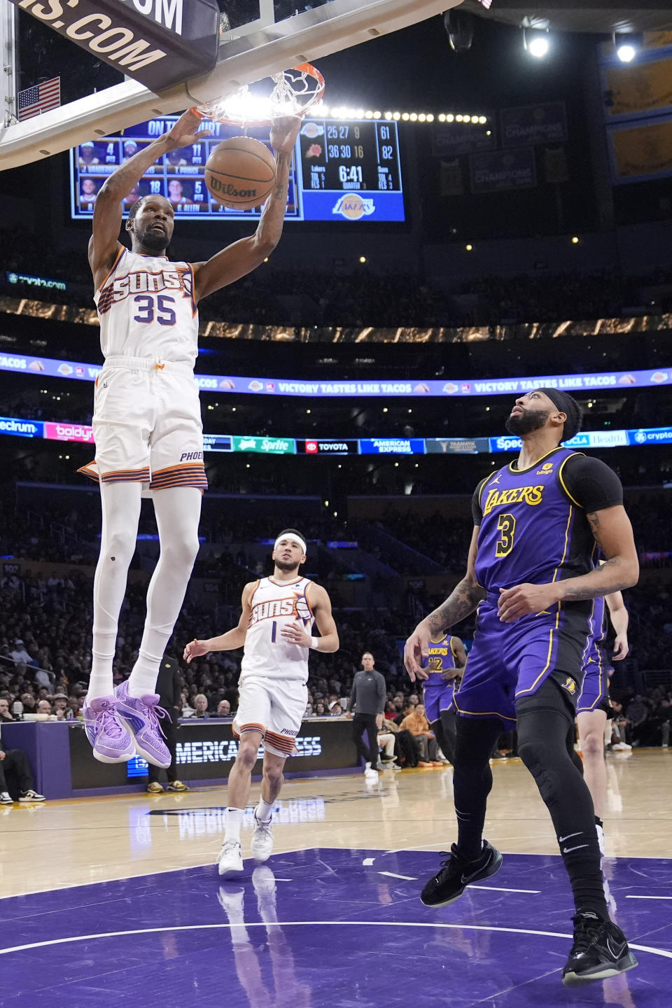 Phoenix Suns forward Kevin Durant, left, dunks as Los Angeles Lakers forward Anthony Davis, right, defends while guard Devin Booker watches during the second half of an NBA basketball game Thursday, Jan. 11, 2024, in Los Angeles. (AP Photo/Mark J. Terrill)