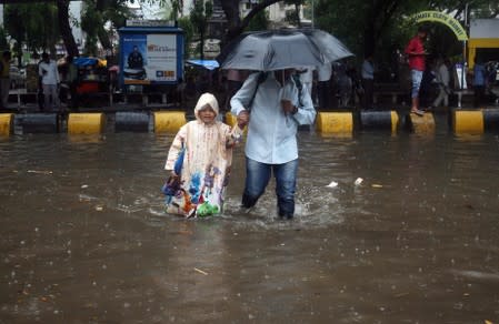 A man and his daughter wade through a waterlogged street during heavy rains in Mumbai