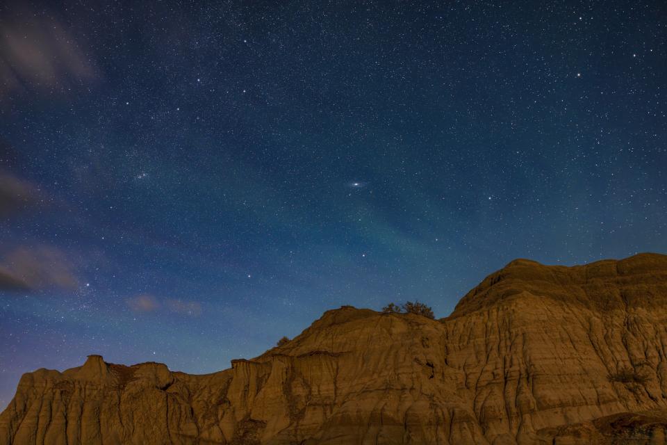 a white wispy disk can be seen among the stars of the night sky