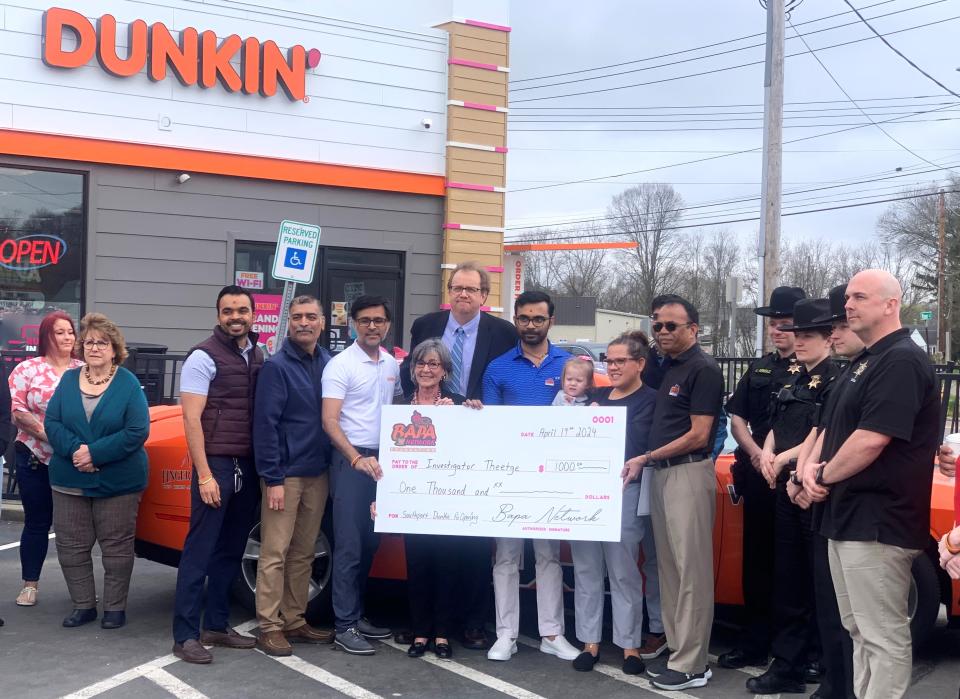 Representatives from the Chemung County Sheriff's Office, right, join local officials and owners of the Dunkin' location on Broadway in Southport on Friday, April 19, 2024 for a check presentation to benefit injured sheriff's investigator Michael Theetge.