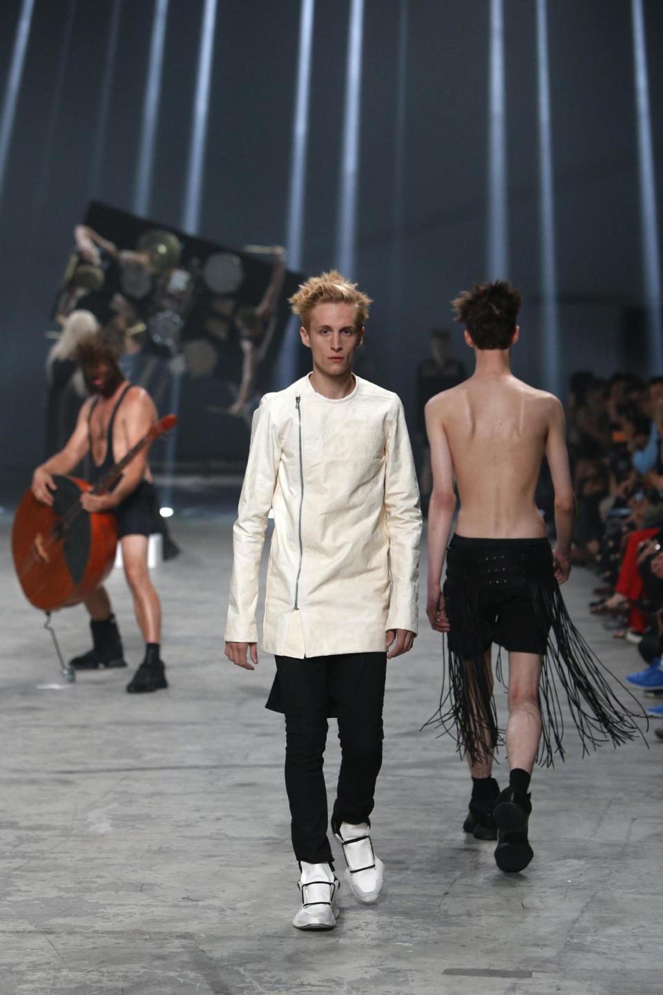 Models, right, wear creations by fashion designer Rick Owens as part of his men's fashion Spring-Summer 2014 collection, presented Thursday, June 27, 2013 in Paris, as Estonian metal/punk band Winny Puhh perform live, rear left. (AP Photo/Francois Mori)