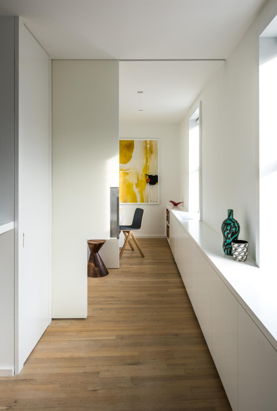 Hallway to home office with white walls and oversized pocket door