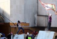 A demonstrator throws a molotov cocktail at riot police during ongoing anti-government protests in Baghdad