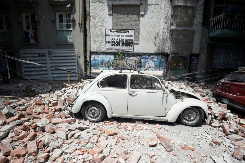 A car is crushed by debris from a damaged building.