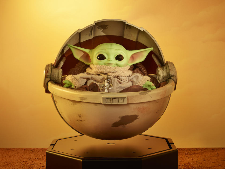 A Baby Yoda plush doll in a floating replica pram from The Mandalorian