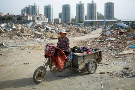 Migrant worker Wang Qin sits on her tricycle that she uses to transport collected scrap materials in a neighbourhood of demolished buildings at the outskirts of Beijing, China October 1, 2017. REUTERS/Thomas Peter