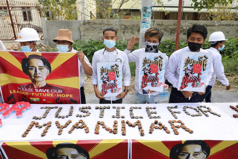 People hold a banner showing the portrait of Aung San Suu Kyi, in Mandalay