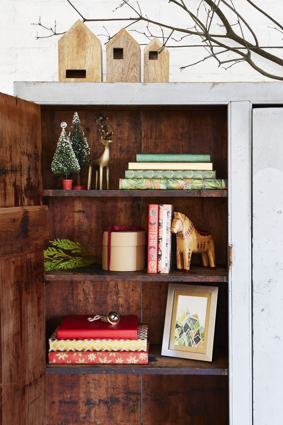 <p>Unos pocos elementos pueden transformar la decoración de tu hogar de "cotidiana" a mágica y navideña. En esta librería una alineación de casas de madera, renos dorados y microárboles traen un país de las maravillas invernal a una estantería.</p>