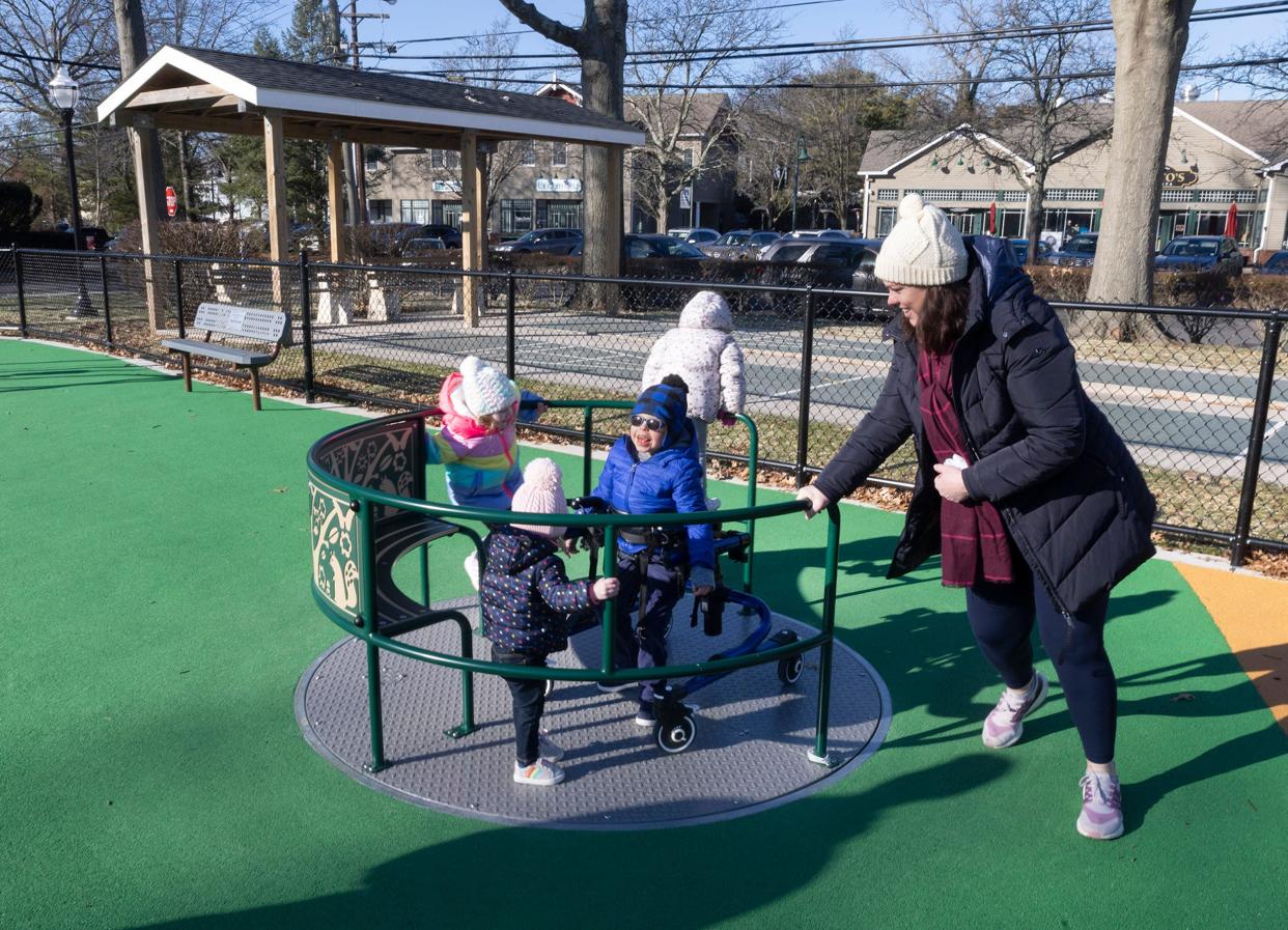 Maureen Anderson pushes her son Raymond and daughters Carolyn and Mary on the ground-level merry-go-round at renovated Curtis Park in Manasquan