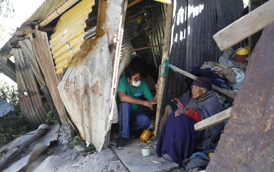 In this May 11, 2020 photo, "Adopt a Grandparent" volunteer Wilmer Gutierrez visits with his “adopted” grandmother, 80-year-old Dominga Aduviri, at her home in La Paz, Bolivia. Gutierrez not only makes sure she has enough to eat but is helping her work through the bureaucracy of getting an identity card. (AP Photo/Juan Karita)