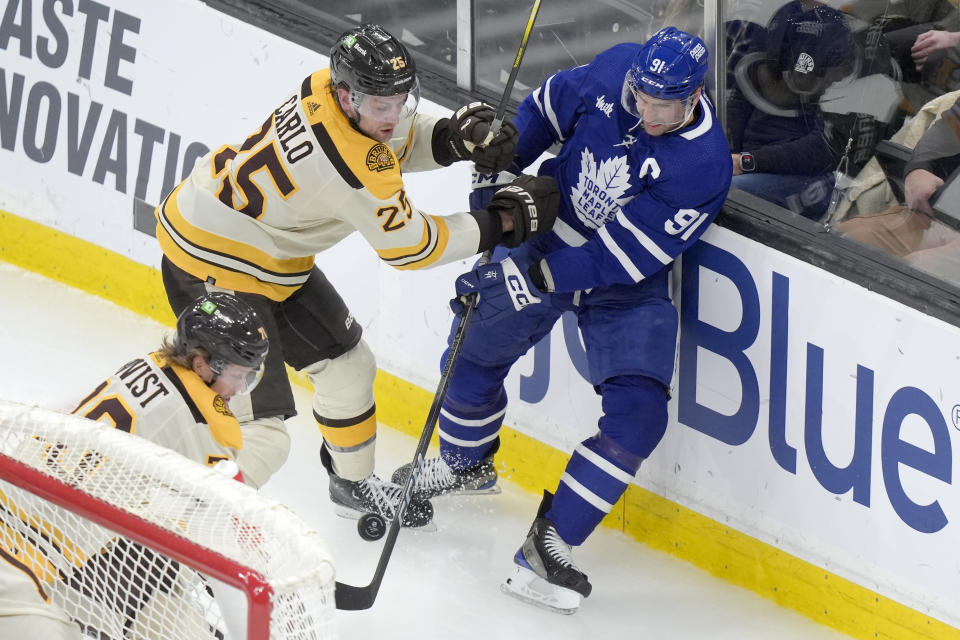 Boston Bruins defenseman Brandon Carlo (25) and Toronto Maple Leafs center John Tavares (91) vie for control of the puck in front of forward Jesper Boqvist (70), left, in the second period of an NHL hockey game, Thursday, March 7, 2024, in Boston. (AP Photo/Steven Senne)