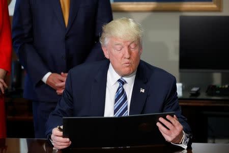 U.S. President Donald Trump looks at an executive order during a signing ceremony with Treasury Secretary Steve Mnuchin at the Treasury Department in Washington, U.S., April 21, 2017. REUTERS/Aaron P. Bernstein