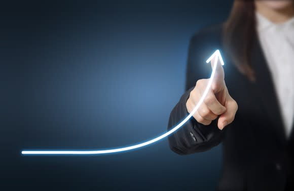 Woman in a business suit using her finger to draw a chart indicating exponential growth