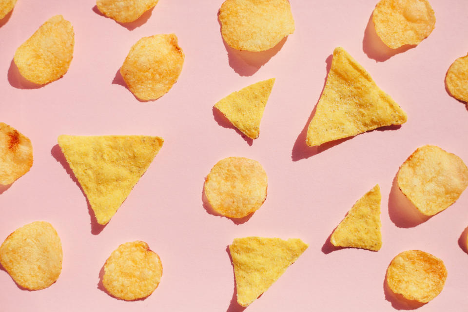 Potato chips pattern over pink background, hard light with shadows. Unhealthy junk food concept.