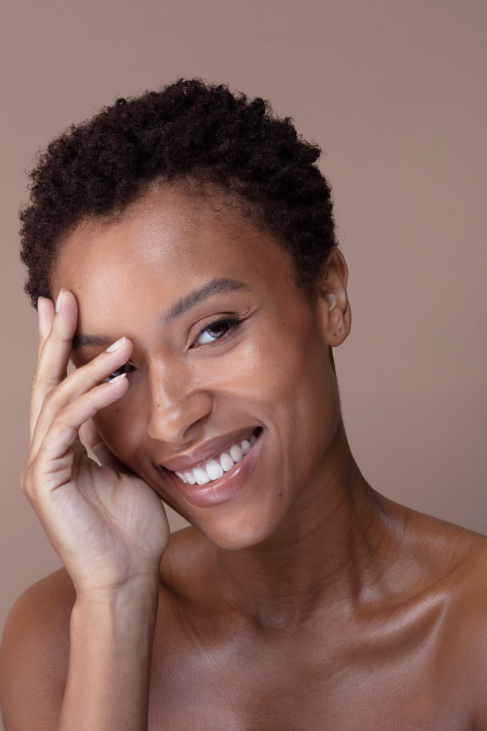 studio portrait of smiling woman touching face