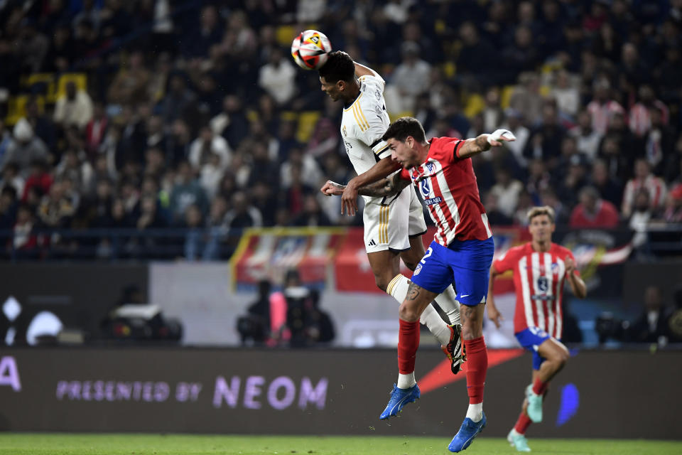 Real Madrid's Jude Bellingham, left, and Atletico Madrid's Jose Gimenez jump for the ball during the Spanish Super Cup semi final soccer match between Real Madrid and Atletico Madrid at Al Awal Park Stadium in Riyadh, Saudi Arabia, Wednesday, Jan. 10, 2024. (AP Photo)