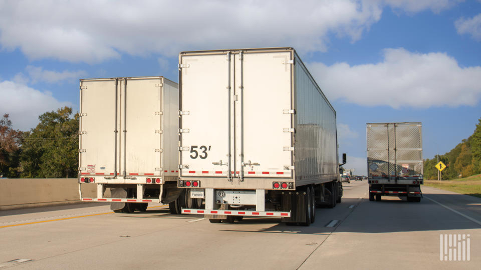 a rearview of three tractor-trailers on a highway