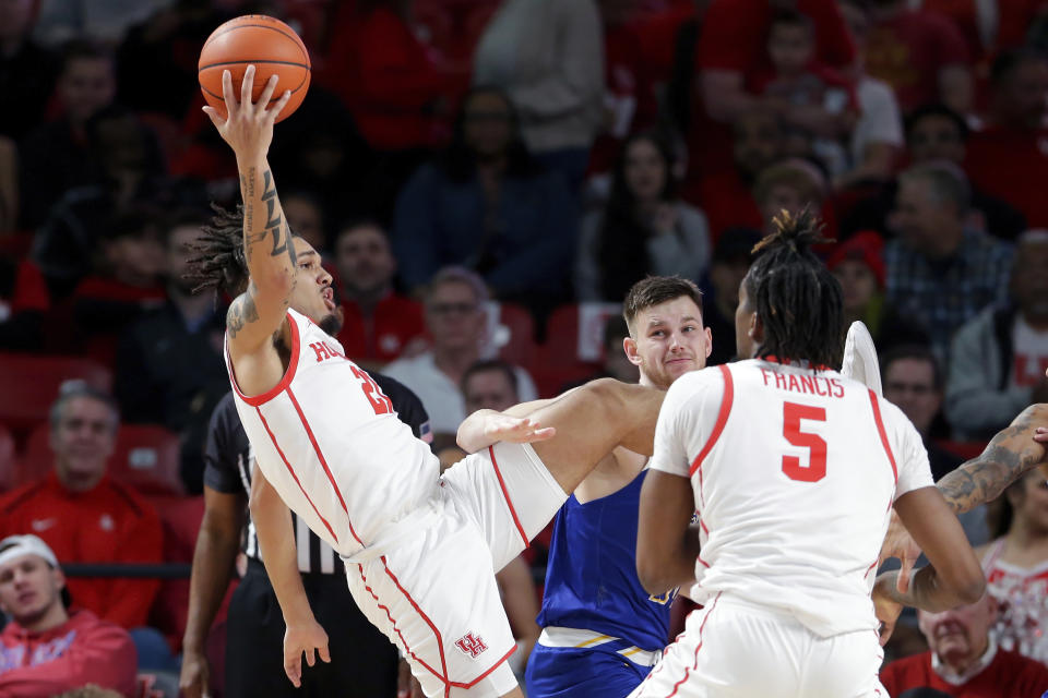 Houston guard Emanuel Sharp, left, falls backward on a rebound past McNeese State forward Roberts Berze, rear, and Houston forward Ja'Vier Francis (5) during the first half of an NCAA college basketball game Wednesday, Dec. 21, 2022, in Houston. (AP Photo/Michael Wyke)