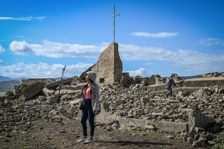 Una mujer toma fotos cerca de las ruinas de una iglesia en la antigua ciudad de Pantabangan, en la provincia de Nueva Écija, Filipinas, el 26 de abril de 2024 (JAM STA ROSA)