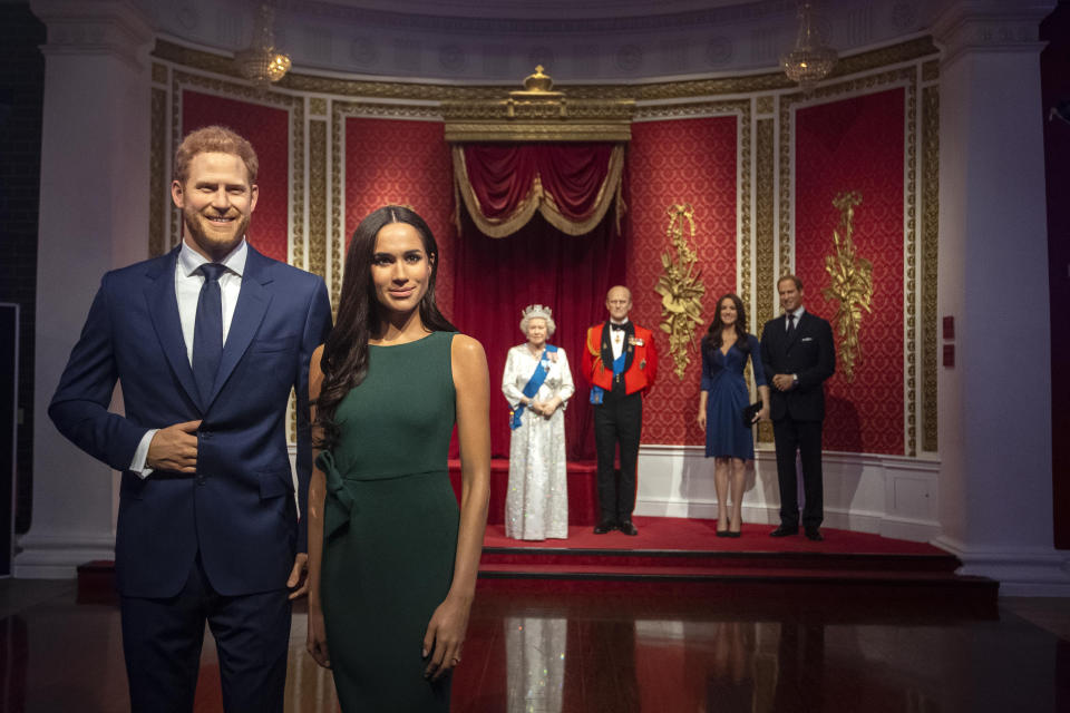 The figures of Britain's Prince Harry and Meghan, Duchess of Sussex, left, are moved from their original positions next to Queen Elizabeth II, Prince Philip and Prince William and Kate, Duchess of Cambridge, at Madame Tussauds in London, Thursday Jan. 9, 2020. Madame Tussauds moved its figures of Prince Harry and Meghan, Duchess of Sussex from its Royal Family set to elsewhere in the attraction. (Victoria Jones/PA via AP)