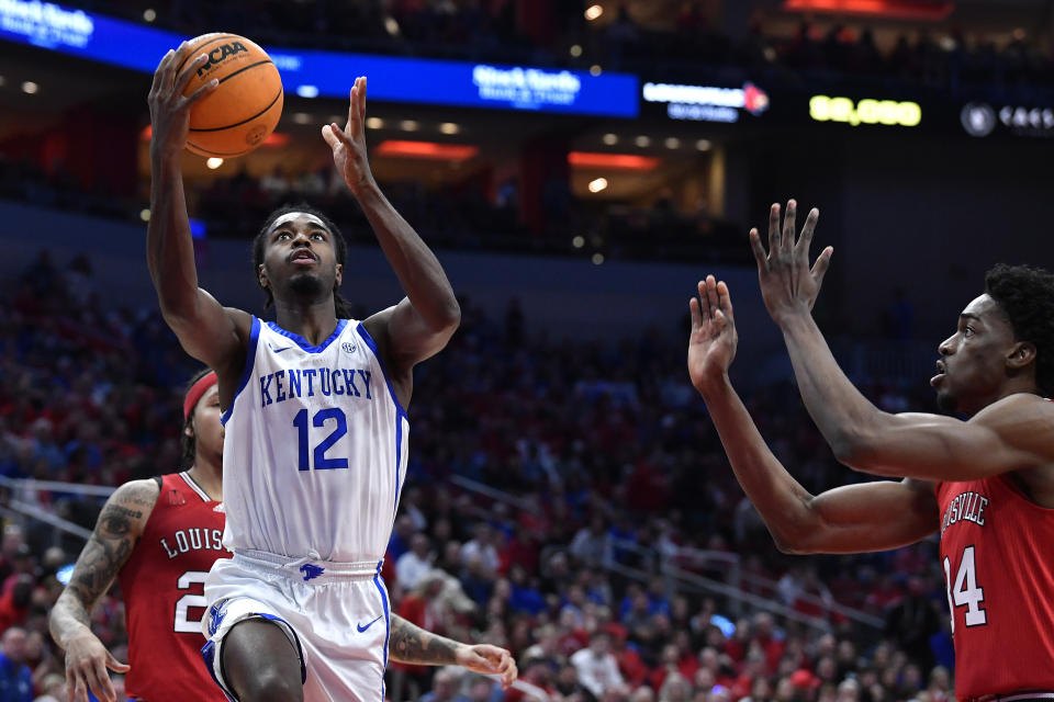 Kentucky guard Antonio Reeves (12) drives for a layup ahead of Louisville forward Emmanuel Okorafor, right, during the first half of an NCAA college basketball game in Louisville, Ky., Thursday, Dec. 21, 2023. (AP Photo/Timothy D. Easley)