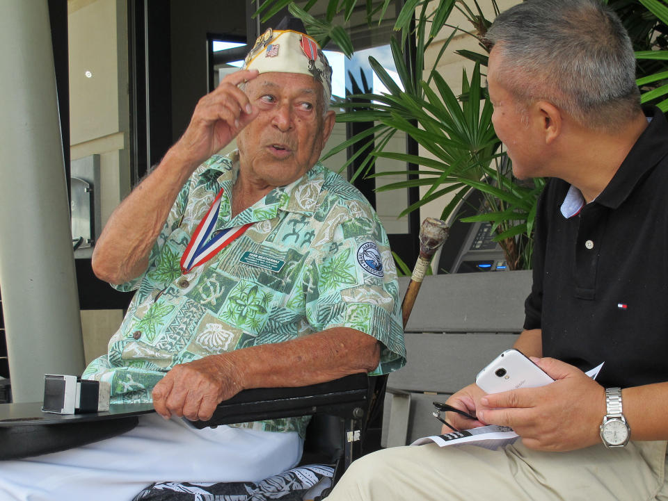 In this photo taken Nov. 22, 2013, Herb Weatherwax, left, talks to a visitor in Pearl Harbor, Hawaii. The 96-year-old retired electrician is one of four Pearl Harbor survivors who volunteers to greet people at the historic site. On Saturday is the 72nd anniversary of the 1941 attack by Japan on Pearl Harbor. (AP Photo/Audrey McAvoy)