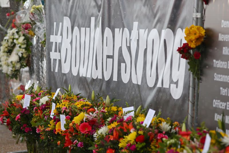 People leave flowers at the site of a mass shooting at King Soopers grocery store in Boulder