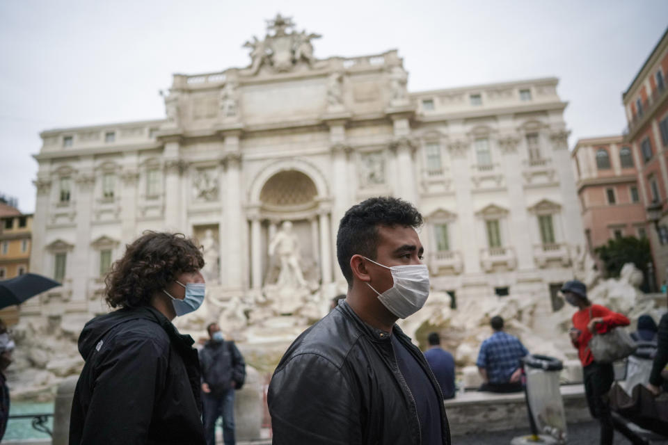 People wear face masks to prevent the spread of COVID-19 as they walk past the Trevi Fountain, in Rome, Saturday, Oct. 3, 2020. As of Saturday it is mandatory to wear masks outdoors in Lazio, the region that includes Rome. (AP Photo/Andrew Medichini)