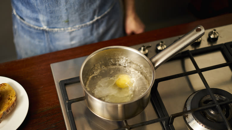 Person poaching an egg in a pot