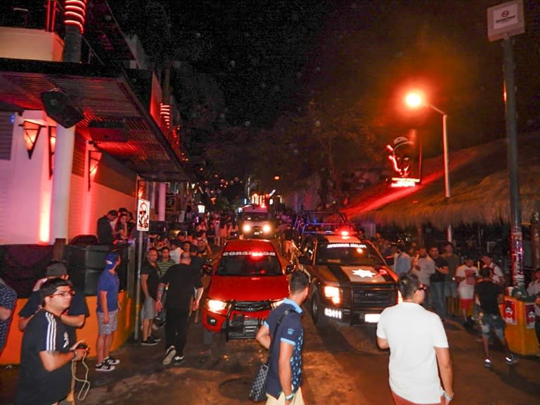 People look on as firefighters and police patrol the Blue Parrot nightclub in Playa del Carmen, Mexico where 5 people were killed, including three foreigners, during a music festival on January 16, 2017