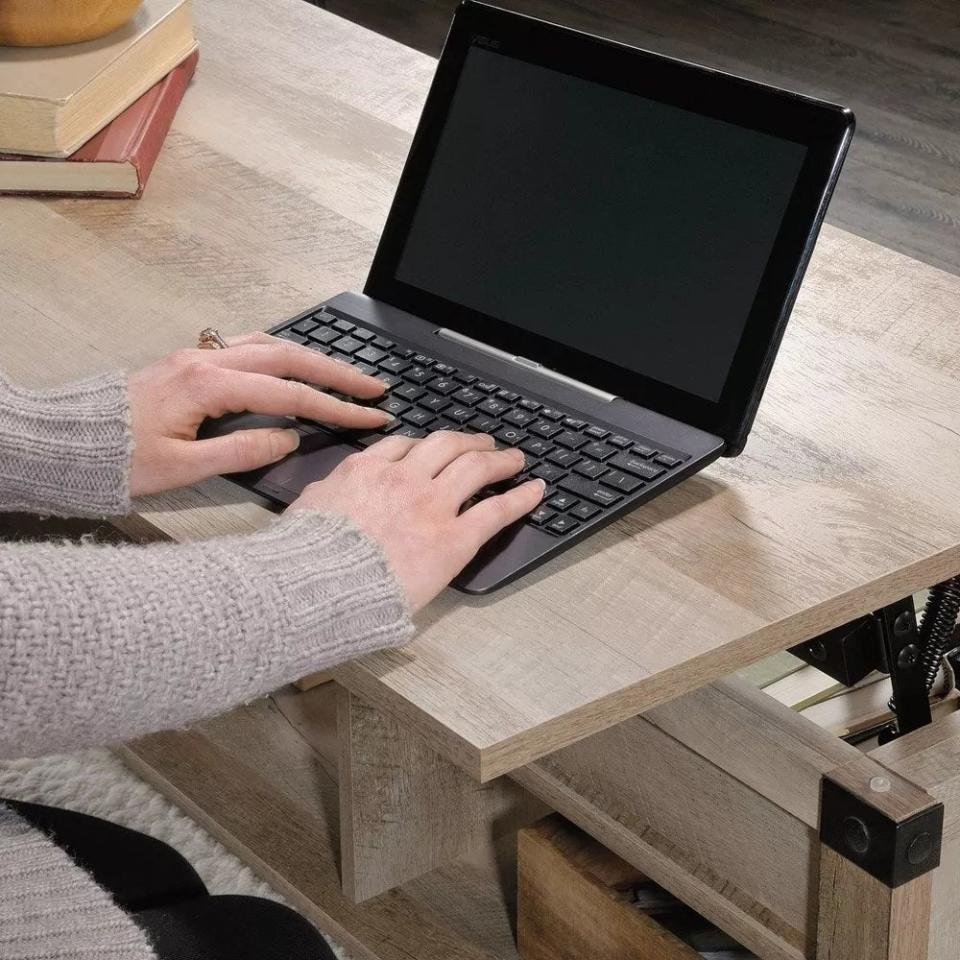 The coffee table, top lifted and being used as a computer desk