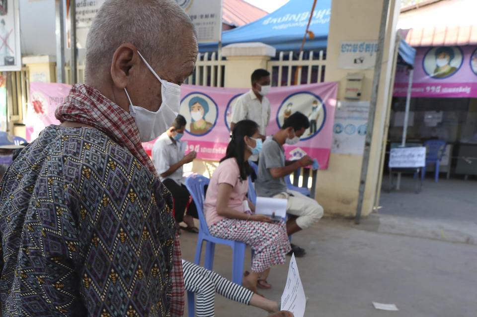 An elderly woman, left, heads to receive a shot of fourth dose of the Pfizer's COVID-19 vaccine at a heath center in Phnom Penh, Cambodia, Friday, Jan. 14, 2022. Cambodia on Friday began a fourth round of vaccinations against the coronavirus, following the recent discovery of cases of the omicron variant, with high-risk groups being the first to receive them. (AP Photo/Heng Sinith)
