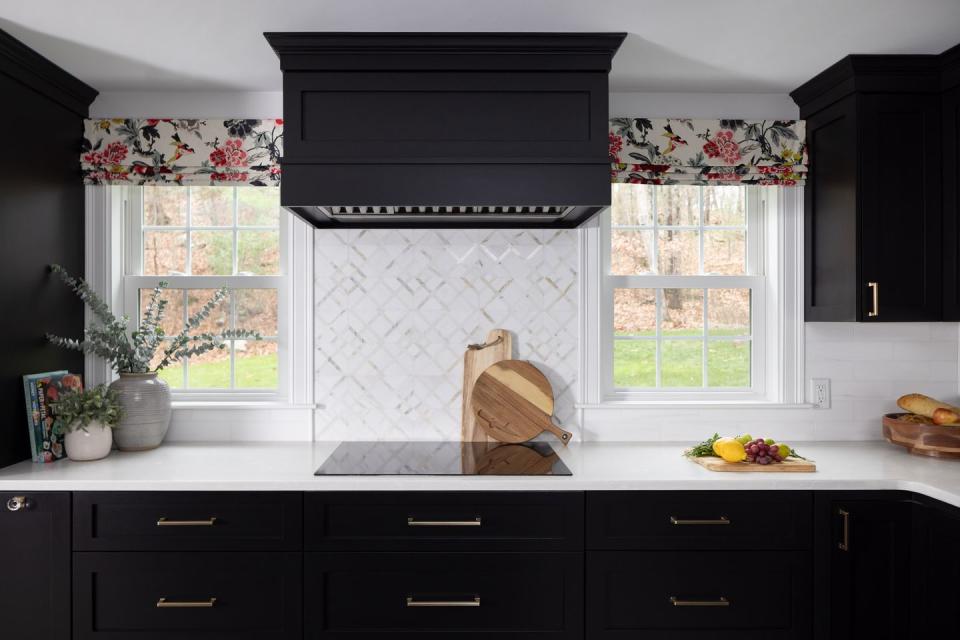 a kitchen with black cabinets and floral curtains
