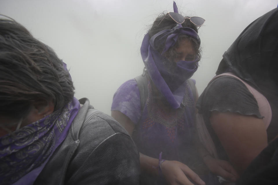 Demonstrators are engulfed with fire retardant after being sprayed by the police with a fire extinguisher at a barricade protecting the National Palace during a march to commemorate International Women's Day and protest against gender violence, in Mexico City, Monday, March 8, 2021. (AP Photo/Ginnette Riquelme)