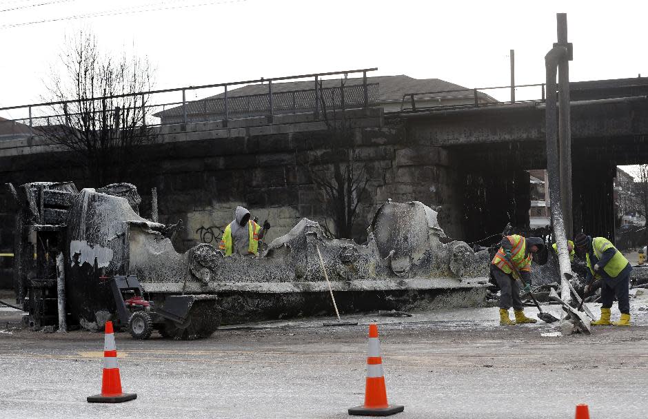 Crews clean up the site where a tanker overturned and burst into flames early in the morning near train tracks on Route 21 in Newark, N.J., Thursday, March 13, 2014. The tanker burst into flames after colliding with a car on McCarter Highway adjacent to Amtrak's Northeast Corridor rail line in Newark at about 1:45 a.m. Thursday. That caused problems for Amtrak's signals and overhead wires. Amtrak service is running with minor delays. (AP Photo/Julio Cortez)