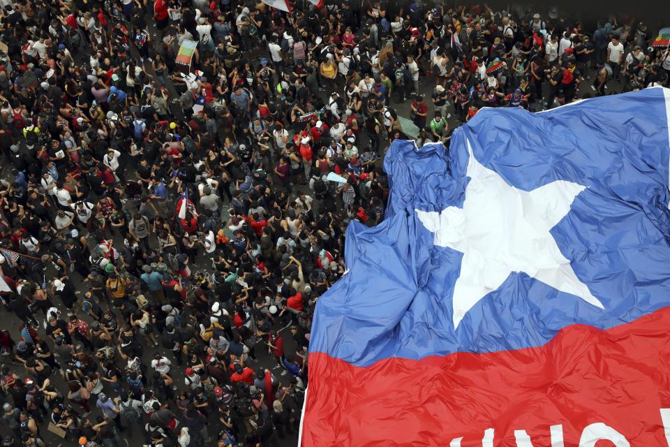 People gather during an anti-government protest in Santiago, Chile, Friday, Oct. 25, 2019. At least 19 people have died in the turmoil that has swept the South American nation. The unrest began as a protest over a 4-cent increase in subway fares and soon morphed into a larger movement over growing inequality in one of Latin America's wealthiest countries. (AP Photo/Rodrigo Abd)