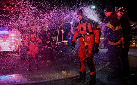 A rescue diver is hosed off with fresh water after pulling victims from the submerged helicopter - Credit: Darren Ornitz/Reuters